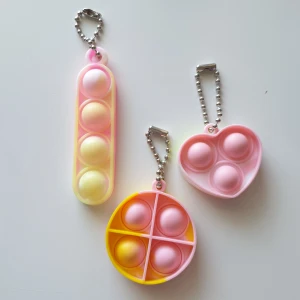 3st rosa/gul popit, fidget toys, nyckelring  - Pop-it, fidget toys  Form: cirkel, avlång, hjärta, Färg: rosa och gul,  Antal: 3st, Skick: nya/oanvända