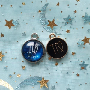 Virgo hängsmycken i silver och guld - Två superfina hängsmycken med Jungfruns stjärntecken. Det ena har en blå bakgrund med stjärnor och texten 'Virgo' i silver, medan det andra har en svart bakgrund med en guldig symbol och text. Perfekta för att göra ditt halsband personligt!