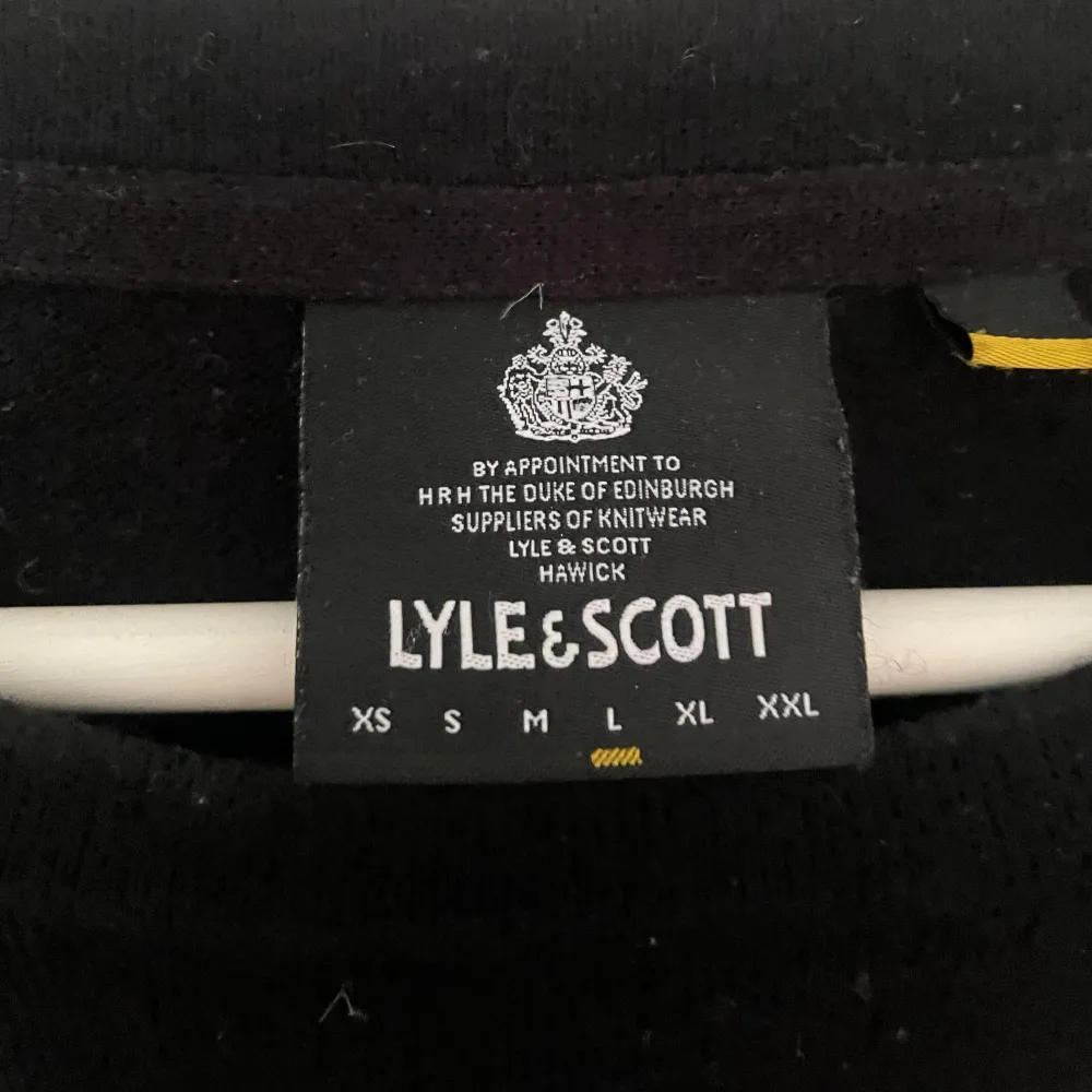 Säljer en stilren svart tröja från Lyle & Scott i storlek M. Tröjan har en klassisk design med ett litet gult emblem på bröstet. Perfekt för både vardag och lite finare tillfällen. Den är långärmad och gjord i ett mjukt material som känns skönt mot huden.. Tröjor & Koftor.