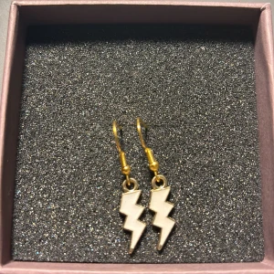 Blixtformade örhängen i guld och silver - Snygga och trendiga örhängen i form av blixtar. De har en cool kombination av guld och silver som verkligen sticker ut. Perfekta för att ge din outfit en edgy touch!