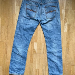 Nudie jeans, hank ray - Ett par Nudie jeans i modellen ”Hank ray”   Längd, ca 103cm.  Midja, ca 42 cm.  Benöppning, ca 19-cm . De har ett ihopsytt hål under fickan samt en fläck på bakre vaden på de högra benet, lite slitage vid benöppningen. Förhandlingsbart pris
