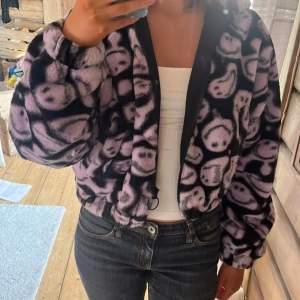Smiley jacka - Supermysig teddyjacka i lila och svart med ett smiley-mönster. Bara använd några få gånger