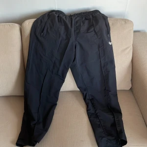 Svarta adidas överdragsbyxor  - Svarta överdragsbyxor i fleece-material. Gott skick. Ordinarie pris var 699kr