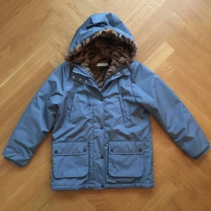 Vinterjacka Stella McCartney Kids stl. 10 år - Jättefin vinterjacka/parka från Stella McCartney Kids, gråblå med leopard innerfoder stl. 10 år. Jackan är nästan oanvänd och skick som ny (Rök och djurfritt hem).  Nypris: ca 2000 kr
