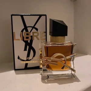 Yves Saint Laurent Libre Eau de Parfum Intense - Säljer en lyxig parfym från Yves Saint Laurent, Libre Eau de Parfum Intense. Flaskan är elegant med en fyrkantig form och en svart, geometrisk kork. Den har en gyllene YSL-logga som omsluter flaskan.  Luktar så gott och HELT oanvänd, säljer pga att jag köpte fel och ska köpa ny🥰super fint flaska som också passar som dekoration 