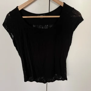 Svart kortärmad topp - Snygg svart topp från MAXX i ett lätt och luftigt material. Den har korta ärmar och en rund halsringning. Perfekt för både vardag och festliga tillfällen. Toppen är i bra skick och passar till många olika outfits.