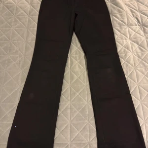 Svarta byxor från H&M - Säljer ett par svarta byxor från H&M i mycket bra skick. De har en dragkedja och knapp framtill samt fickor bak. Byxorna är högmidjade och har en straight passform, perfekta för både vardag och fest. Materialet känns mjukt och bekvämt.