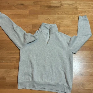 Grå tröja med dragkedja från Zara - Säljer en stilren grå tröja från Zara i storlek L. Den har en halv dragkedja framtill och är perfekt för både vardag och avslappnade tillfällen. Tröjan är i mycket bra skick och passar bra till höst och vår. Superbekväm och lätt att matcha med andra plagg!