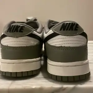 Säljer ett par Nike Dunk sneakers i grönt och vitt. De har en klassisk design med snörning och Nike-logga på sidan. Skorna är i bra skick och perfekta för vardagsbruk. Tillverkade i syntetmaterial med en bekväm passform. Lite creased men går att fixa. 9/10 skick