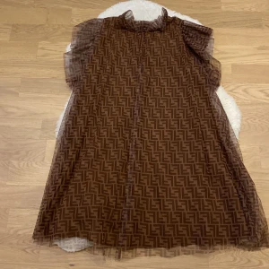 Brun mönstrad klänning med volangärmar - Säljer en superfin brun klänning med ett coolt geometriskt mönster. Den har volangärmar och en luftig passform, perfekt för både vardag och fest. Materialet känns lätt och bekvämt. Klänningen har en knapp i nacken för enkel påklädning. Passar perfekt för höst och vår!🤎