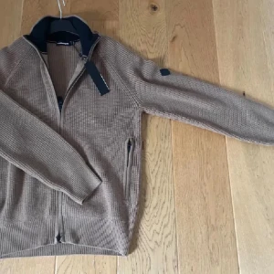 Cardigan J.Lindeberg - Säljer en helt ny stickad tröja från J.Lindeberg med zip i storlek S men passar även M. Den är köpt för 2000 men mitt pris är 900. Skriv vid frågor eller funderingar.