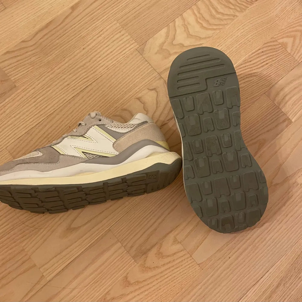 Säljer ett par snygga och bekväma begia, gråa, vita och gula sneakers från New Balance i modellen 57/40. De har en stilren design med snörning och en robust sula för extra komfort. Perfekta för både vardag och träning. BARA ANVÄNDA INOMHUS ett få tal gånger och är i mycket bra skick! Ny pris cirka 1600kr. Skor.