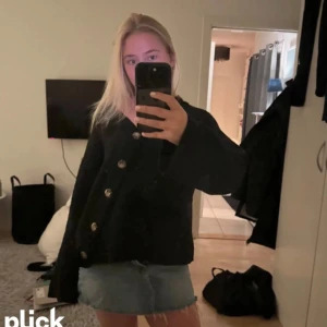 Svart kofta med knappar - Säljer en snygg svart kofta med stora knappar framtill. Perfekt för höst och vinter, den är både stilren och bekväm. Koftan har även långa armar!!