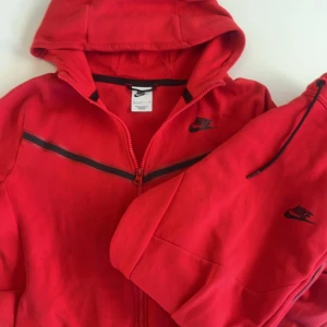 Röd fleece och byxor från Nike XL i barn - Säljer en snygg röd fleece och matchande byxor från Nike. Skicket är acceptabelt och har en fin röd färg. Köpt från Zalando. Öppen till frågor och kan skicka fler bilder privat👏