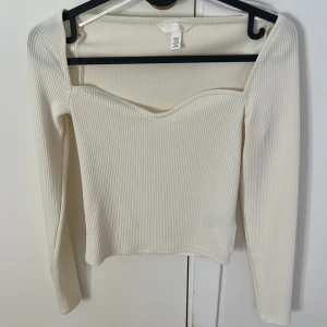 Vit ribbad topp från Zara - Säljer en superfin vit ribbad topp från h&m i storlek XS. Den har en elegant offshoulder-design och långa ärmar, perfekt för både vardag och fest. Toppen är i mycket bra skick och passar perfekt till både jeans och kjol.