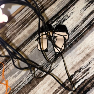 Svarta sandaler med snörning - Snygga svarta sandaler med snörning som ger en elegant look. Perfekta för sommarens alla fester. De har en stilren design med en fyrkantig tå och långa remmar som kan knytas runt ankeln.