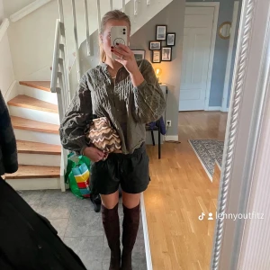 Olivgrön blus med volangdetaljer - Säljer en snygg olivgrön blus med volangdetaljer. Perfekt för höst och vår! Blusen har långa ärmar och en lös passform som ger en avslappnad stil. Den är gjord i ett lätt och bekvämt material, perfekt för både vardag och fest. Passar bra med både jeans och kjol. 🥰