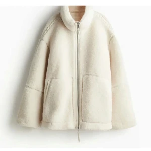 Vit teddyjacka med dragkedja - Supermysig vit teddyjacka som är perfekt för höst och vår. Den har en hög krage och fickor framtill. Jackan är i ett fluffigt material som håller dig varm och stilren. 