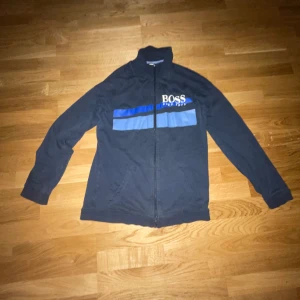 Svart jacka från Boss - Säljer en snygg mörkblå zipup från Boss med blåa och ljusblåa detaljer. Den har en dragkedja framtill och långa ärmar. Perfekt för en casual look eller en utekväll. Passar bra till både jeans och chinos. Hör av dig vid intresse!😀😀