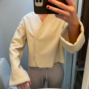 Beige omlottjacka/kofta från Gina Tricot - Säljer en superfin beige omlottjacka/kofta från Gina Tricot i storlek S. Den har långa ärmar och en stilren design med dekorativa sömmar. Perfekt för både vardag och fest! 🥰