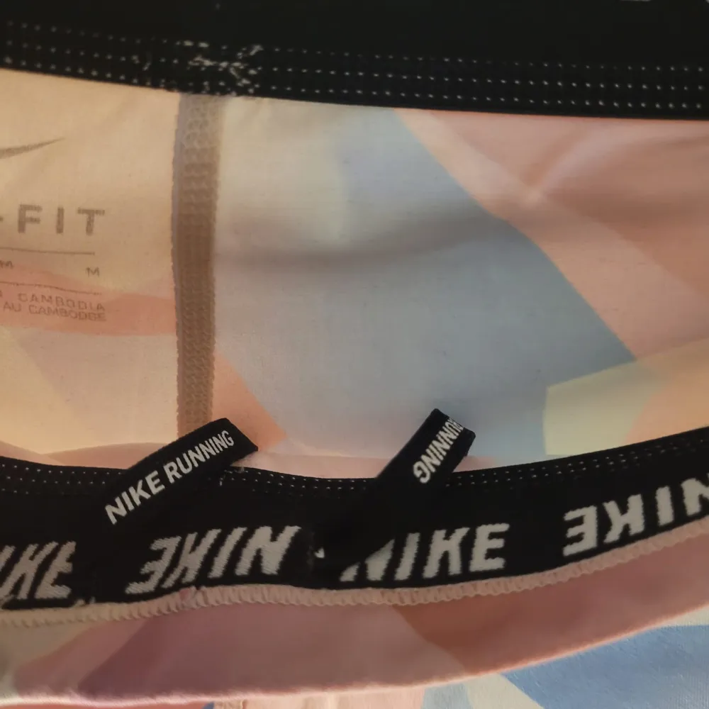 Säljer ett par snygga flerfärgade leggings från Nike i storlek M. De har ett geometriskt mönster i rosa, blått och orange. Perfekta för träning med Dri-FIT material som håller dig torr och bekväm. Midjan är elastisk med Nike-logga för extra stil. Passar perfekt för gymmet eller löprundan!. Farkut & Housut.