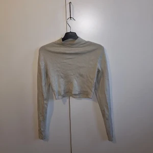 Beige croppad tröja från Weekday - Säljer en snygg beige croppad tröja från Weekday i storlek S. Tröjan är ribbad och har långa ärmar, perfekt för en stilren look. Passar bra till både vardag och fest. Den är använd och har därför lite noppror på ryggen. Denna tröjan ligger ute på flera sidor. 