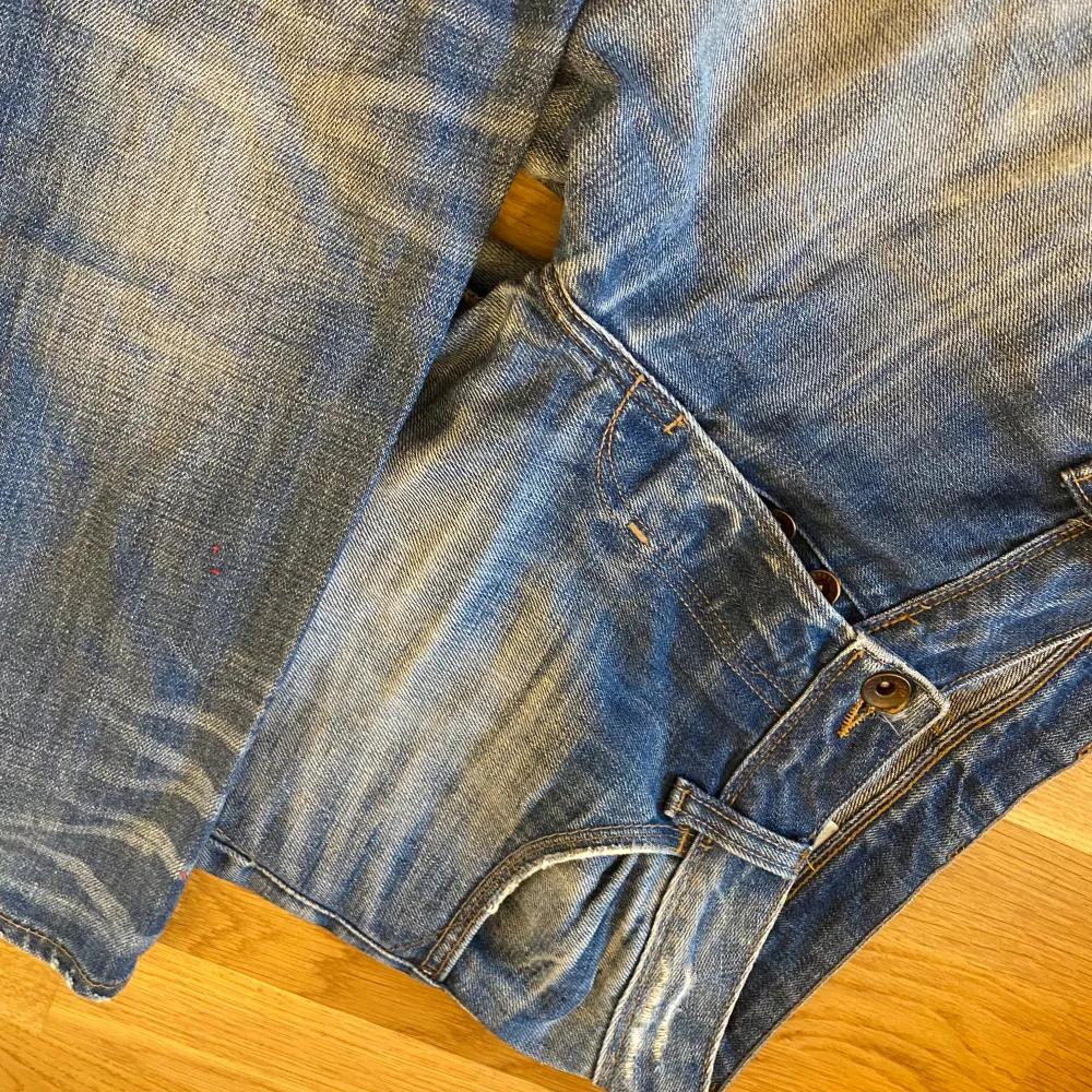 Säljer ett par snygga blå bootcut lågmidjade jeans med coola slitningar. Dem är vintage från hm 2000 talet . Jeans & Byxor.