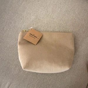 Beige necessär med dragkedja - Säljer en snygg beige necessär i manchester med dragkedja. Perfekt för att hålla ordning på dina toalettartiklar när du reser. Den har en stilren design och är i nytt skick. Passar perfekt i resväskan eller som en liten väska i handväskan.