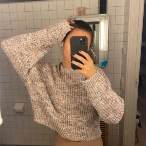 Flerfärgad stickad tröja - Säljer en supermysig flerfärgad stickad tröja i croppad modell. Perfekt för höst och vinter med sina långa ärmar och mjuka material. Tröjan har en härlig mix av färger som ger den ett unikt utseende. Passar perfekt till både jeans och kjol för en avslappnad look.