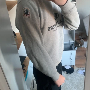 Grå sweatshirt från Parajumpers - Säljer en grå sweatshirt från Parajumpers i bra skick. Med patch på armen pris kan diskuteras. Storlek S men passar till M också