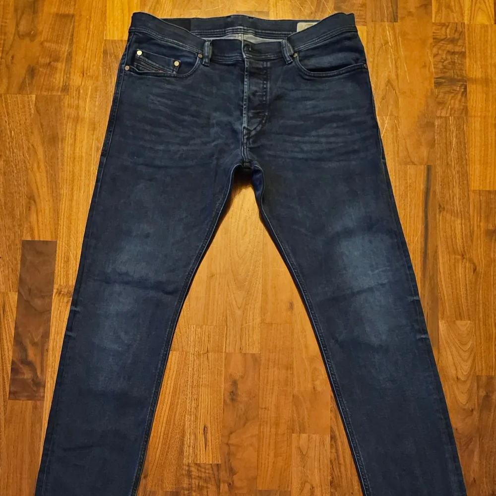 Säljer ett par snygga mörkblå jeans från Diesel, modell Tepphar. De är i bra skick och har en slim passform som sitter perfekt. Materialet är en blandning av bomull och lyocell, vilket gör dem både bekväma och hållbara. Perfekta för både vardag och fest!. Jeans & Byxor.