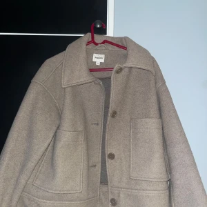 Beige ulljacka från Kappahl  - Säljer en snygg beige ulljacka från Kappahl  i storlek M. Jackan har en klassisk krage och stora fickor framtill. Perfekt för höst och vinter, med en stilren look som passar till det mesta. Knapparna framtill ger en enkel och elegant stängning. Perfekt för dig som vill hålla stilen i kylan! Jackan är ny utan prislapp. Nypris 1000kr