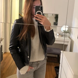 Svart skinnjacka - Säljer en snygg svart skinnjacka i mycket bra skick. Den har en klassisk design med dragkedja och passar perfekt för höst och vår. Jackan har en normal passform och är långärmad, vilket gör den både stilren och bekväm🍂