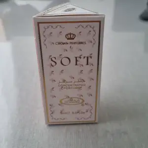 Säljer en elegant och koncentrerad parfym från Crown Perfumes, kallad Soft. Förpackningen är vit med guld- och rosa detaljer, vilket ger en lyxig känsla. Perfekt för den som vill ha en subtil men ändå märkbar doft. Flaskan är liten och smidig att ta med sig.