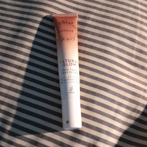 Natural Glow Skin Tone Perfector - Säljer en Lumene Natural Glow Skin Tone Perfector i nyansen 2 Perfect Tan. Denna veganska produkt ger en naturlig lyster och jämnar ut hudtonen. Perfekt för en fräsch och strålande look. Tuben innehåller 20 ml och är lätt att ta med sig i väskan. Lite mer en halva kvar i den