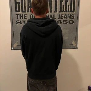 Mörkblå hoodie från Ralph Lauren - Säljer en snygg mörkblå hoodie från Ralph Lauren i bra skick. Den har en dragkedja framtill och en liten röd logga på bröstet. Perfekt för höst och vår, med sköna långa ärmar och en mysig huva med vita snören. Passar både till vardags och chillkvällar.