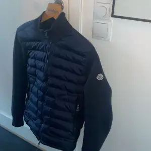 Säljer en snygg mörkblå dunjacka från Moncler i mycket bra skick. Jackan har en quiltad design med dragkedja framtill och långa ärmar. Perfekt för höst och vinter, håller dig varm och stilren. Moncler-loggan syns på ärmen. Passar både till vardags och lite finare tillfällen.