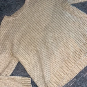 Beige stickad tröja - Mysig beige stickad tröja i bra skick. Perfekt för kyliga höst- och vinterdagar. Tröjan har en normal passform med långa ärmar och ribbade detaljer vid ärmslut och nederkant. 