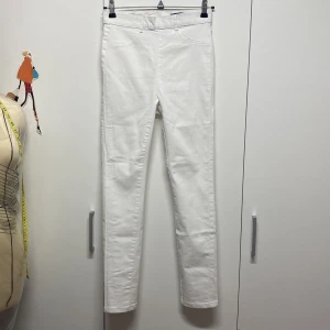 Vita byxor med dragkedja i nytt skick - Säljer ett par stilrena vita byxor i nytt skick. De har en tight passform och är perfekta för både vardag och fest. Byxorna har en dragkedja bak och är gjorda i ett bekvämt bomullsmaterial. Perfekta för vår och sommar!