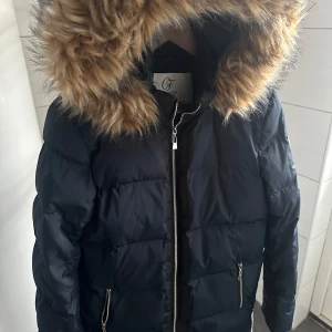 Vinterjacka Chiara Forthi  - Varm vinterjacka i dun från Chiara Forti MILANO. Marinblå stl 34. Ena dragkedjan på sidofickan trasig men påverkar inte funktion och utseende i övrigt annars fint skick.