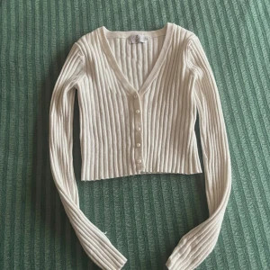 Vit ribbad kofta - Säljer en superfin vit ribbad kofta med v-ringning och pärlor framtill. 🧡