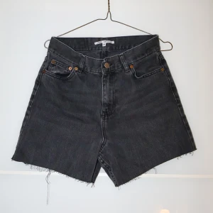 Svarta jeansshorts från Junkyard - Säljer ett par svarta jeansshorts från Junkyard i modellen Kay Girlfriend. De är högmidjade med en rå kant nertill. Perfekta för sommaren och kan stylas med allt från t-shirts till blusar. Använda men i bra skick!