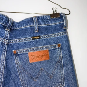 Blå jeans från Wrangler - Säljer ett par klassiska blå jeans från Wrangler i mycket bra skick. De har en straight passform och är tillverkade i slitstarkt denim. Perfekta för både vardag och avslappnade tillfällen. Jeansens ikoniska lädermärke på bakfickan ger en tidlös look. Passar perfekt till en t-shirt eller skjorta!