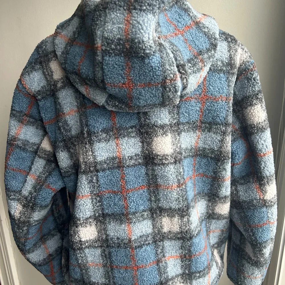 Säljer en supermysig och varm fleecejacka från JW Anderson x Uniqlo. Den har ett snyggt rutigt mönster i blått, grått, vitt och orange. Jackan är långärmad och har en praktisk dragkedja framtill samt en ficka med dragkedja på bröstet. Perfekt för kyliga dagar!. Takit.