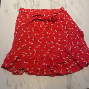 Volangkjol - Röd volangkjol med blommor på. Bra skick.