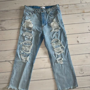 Ljusa jeans med slitningar - Säljer ett par ljusa jeans med coola slitningar på framsidan. De har en avslappnad passform och är perfekta för en casual look. Jeansen är gjorda  i ett bekvämt denimtyg. Perfekta för vår och sommar!