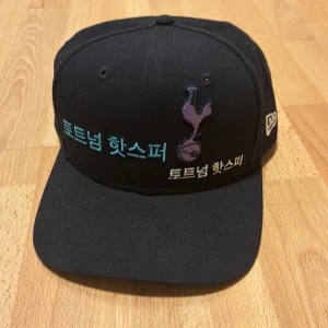 Tottenham Hotspurs New Era Keps Korea - Fet new era keps från Tottenham hotspurs. Det är cool design med massa text på koreanska och flera Hotspurs loggor i olika färger. Knappt använd.