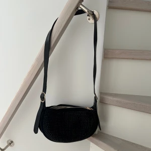 Väska - Väska med justerbart band Bandets totala mått är 114cm Väskans mått är ca 28x17x9cm  Någon mockaimitation med stenar, lite tyngre i och med stenarna så känns rejälare