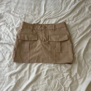 Beige minikjol - En beige minikjol med fickor på framsidan.