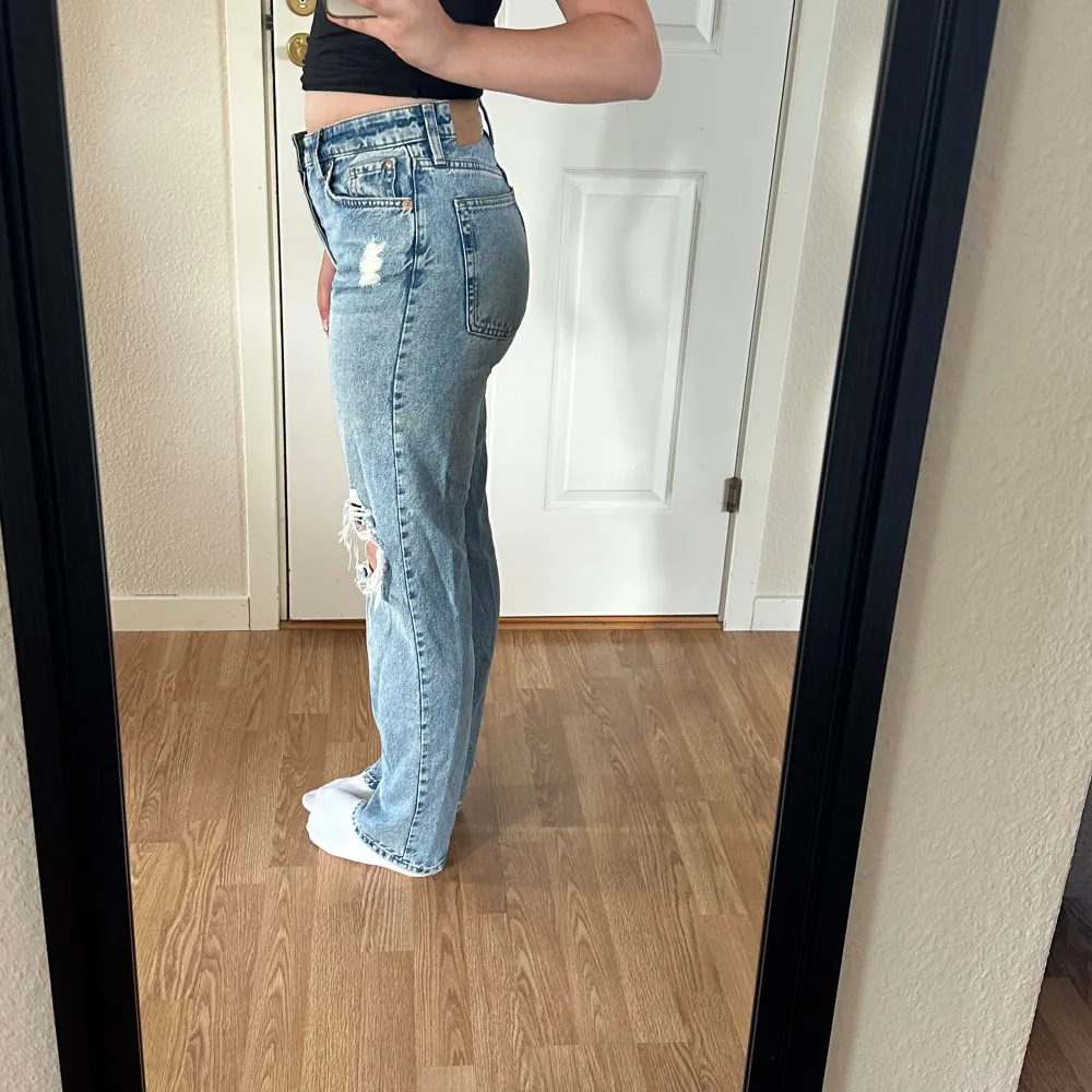 Säljer ett par ljusa jeans med coola slitningar på knäna. De har en hög midja och en straight passform som ger en avslappnad look. Perfekta för en casual outfit! 🕶️. Jeans & Byxor.